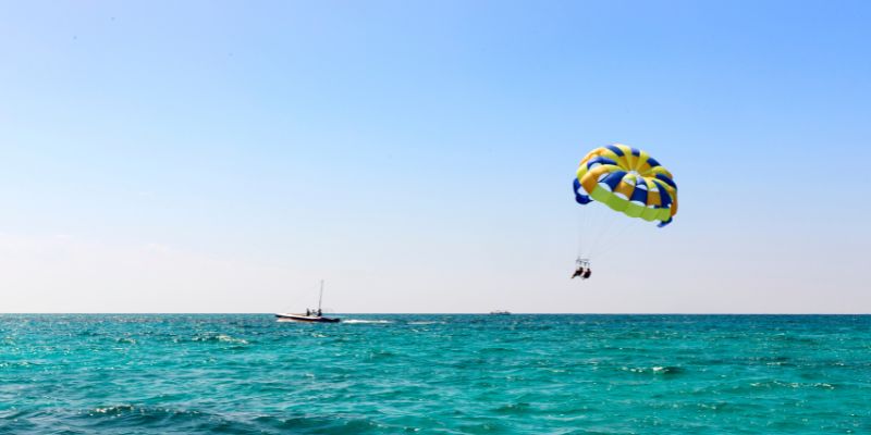 Parasailing vs paragliding comparison showing a person parasailing above the ocean