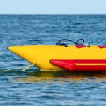 Yellow and red inflatable banana boat floating on the water, ready for thrilling banana boat rides.