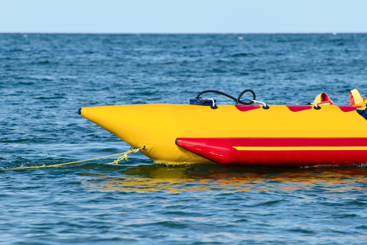 Yellow and red inflatable banana boat floating on the water, ready for thrilling banana boat rides.