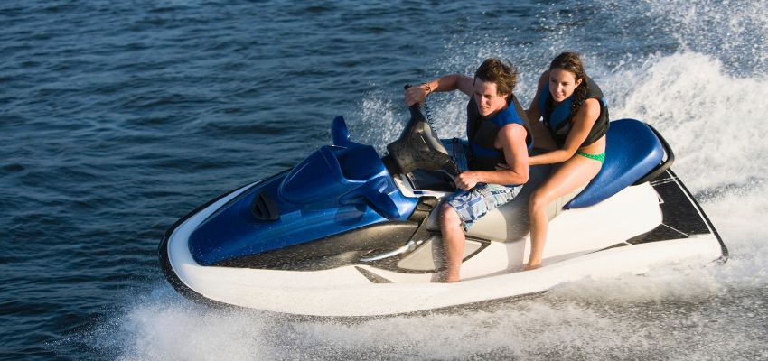 Couple enjoying a ride on a personal watercraft across open water.