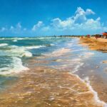 South Padre Island beach in May with visitors relaxing under sun umbrellas.