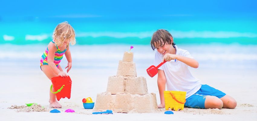 Two children building a detailed sandcastle on the sandy beach, capturing creative and fun things to do in South Padre Island with family like sandcastle building and playtime by the shore.