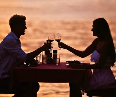 Romantic couple toasting with wine at a sunset beachside dinner, representing the scenic best places to eat in South Padre Island.