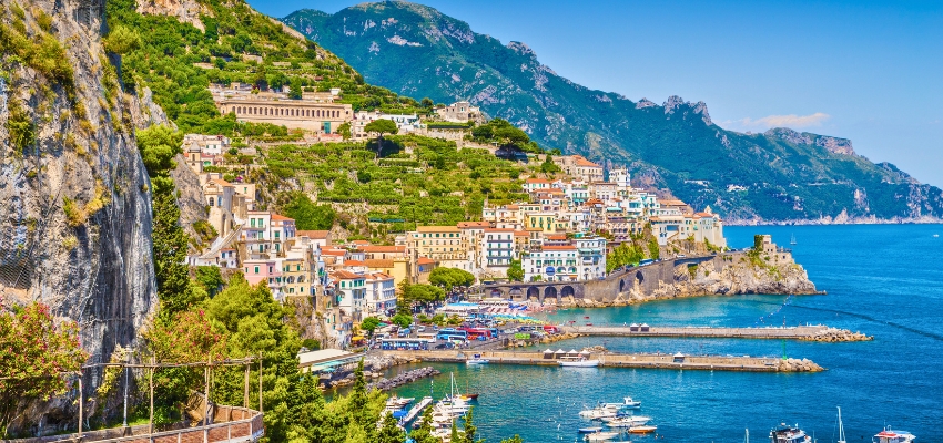 Colorful cliffside villages and boats along the scenic Amalfi Coast in Italy, one of the most breathtaking choices for where to travel in summer