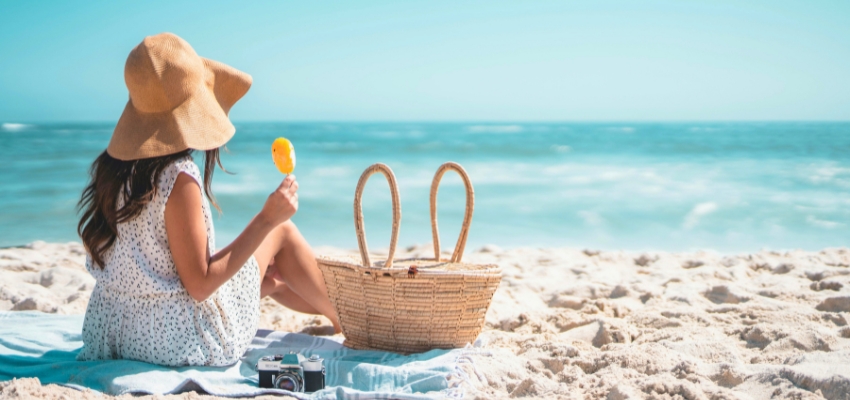 Woman relaxing on the beach with a picnic basket and ice cream, enjoying free things to do in south padre island.