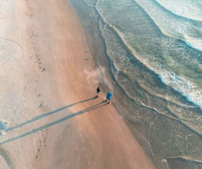 Aerial view of a couple walking the shoreline at sunset, showcasing free things to do in south padre island.