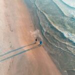 Aerial view of a couple walking the shoreline at sunset, showcasing free things to do in south padre island.