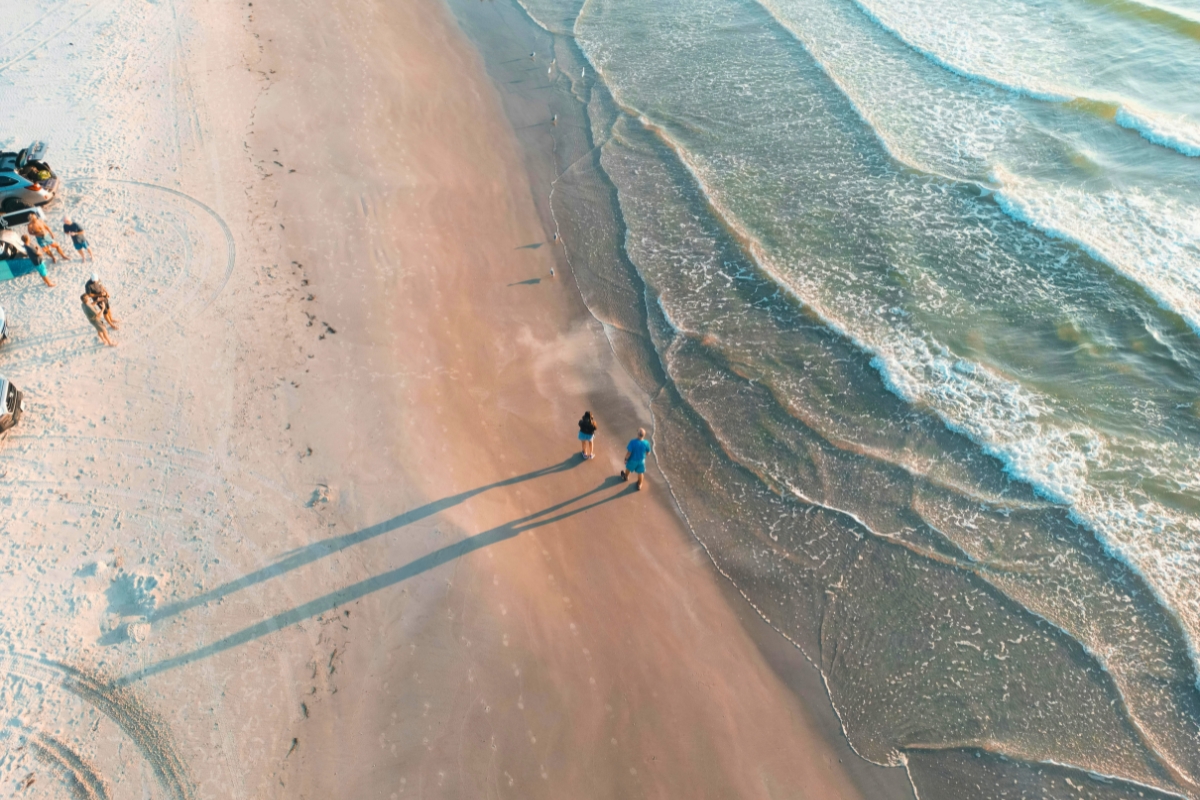 Aerial view of a couple walking the shoreline at sunset, showcasing free things to do in south padre island.