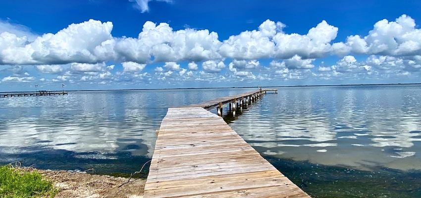 Scenic wooden pier over calm waters under blue skies, a popular free things to do in south padre island