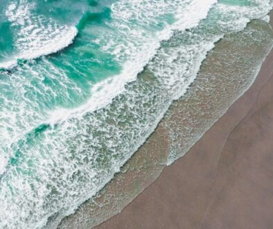 Turquoise waves crashing onto the sand in an aerial view, proving is there a beach in texas with beautiful shoreline scenery