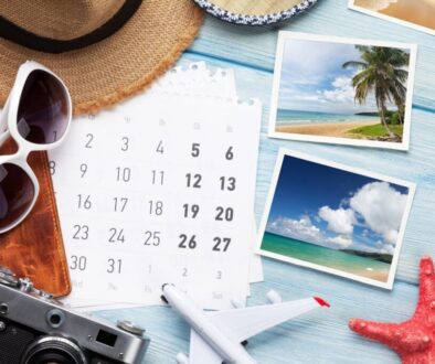 Travel planning flat lay with calendar and beach photos for choosing places to visit this summer.