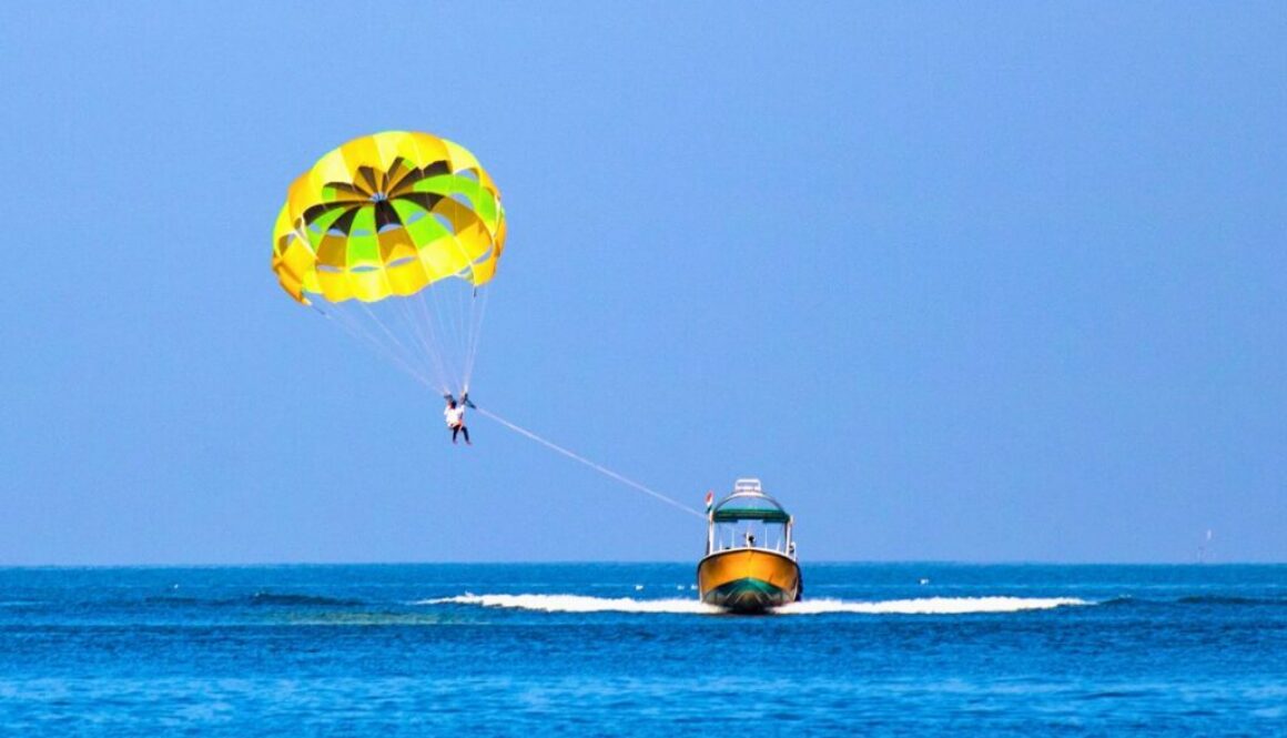 Parasailer gliding over open ocean, a scene that often raises the question is parasailing dangerous.