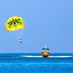 Parasailer gliding over open ocean, a scene that often raises the question is parasailing dangerous.