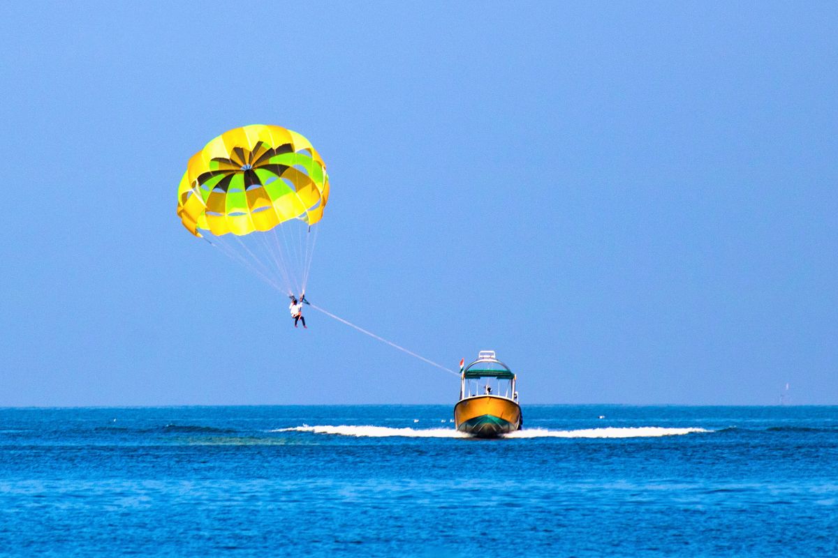 Parasailer gliding over open ocean, a scene that often raises the question is parasailing dangerous.